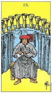 Carta del Nueve de Copas del Tarot Rider Waite: un hombre sentado con los brazos cruzados delante de nueve copas doradas dispuestas en arco.