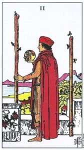 Carta del Dos de Bastos del Tarot Rider Waite: un hombre en lo alto de un castillo sosteniendo un globo terráqueo y un bastón, mirando hacia el mar.