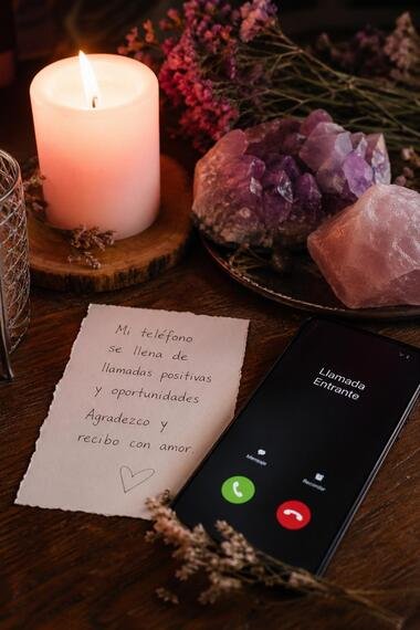 Ritual para atraer llamadas con vela naranja, hojas de laurel y teléfono móvil sobre escritorio elegante.